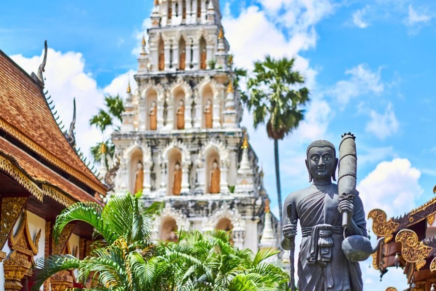 religious figurine near gray concrete mosque under blue and white cloudy sky